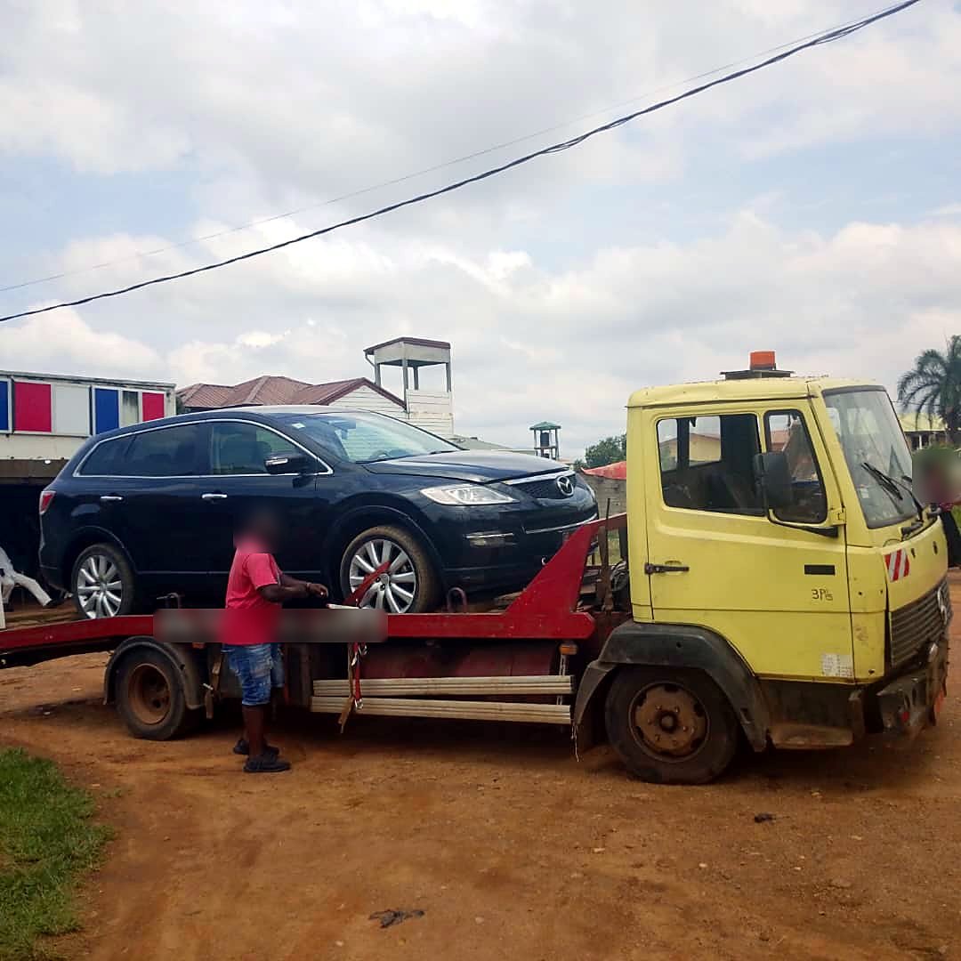Dépanneuse plateau jaune et rouge chargée d’un SUV Mazda CX-9 noir à Bonabéri, Douala, avant son transfert vers Yaoundé