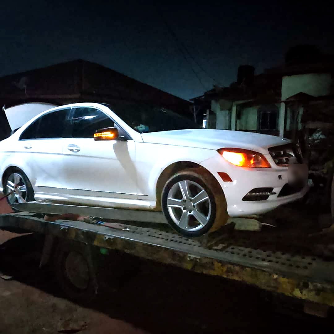 Mercedes Classe C blanche chargée sur une dépanneuse plateau, de nuit, dans une rue de New Bell à Douala